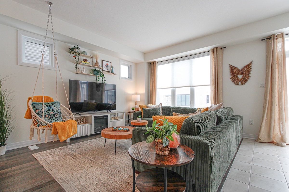 The Harmony House living room: a deep green sofa, mustard cushions and a hanging swing chair
